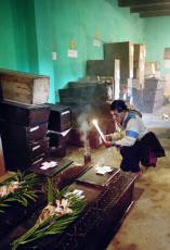 A Mayan priest prays over the coffins containing the remains of his loved ones. Nebaj, 2001