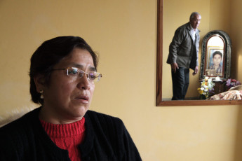 Reynalda Andagua Gonzales talks about her son, Martín Roca Casas, who disappeared in 1993. Javier Roca, Martín’s father, appears in the mirror next to an altar dedicated to the memory of his son. “He was kidnapped, tortured, murdered and incinerated during the government of Alberto Fujimori”. Lima, 2009